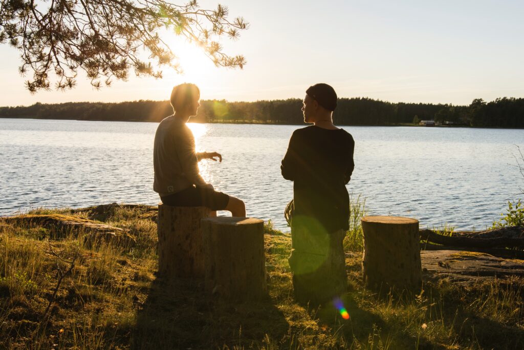 A couple of people in sitting by a lake, representing open-minded discussions.
